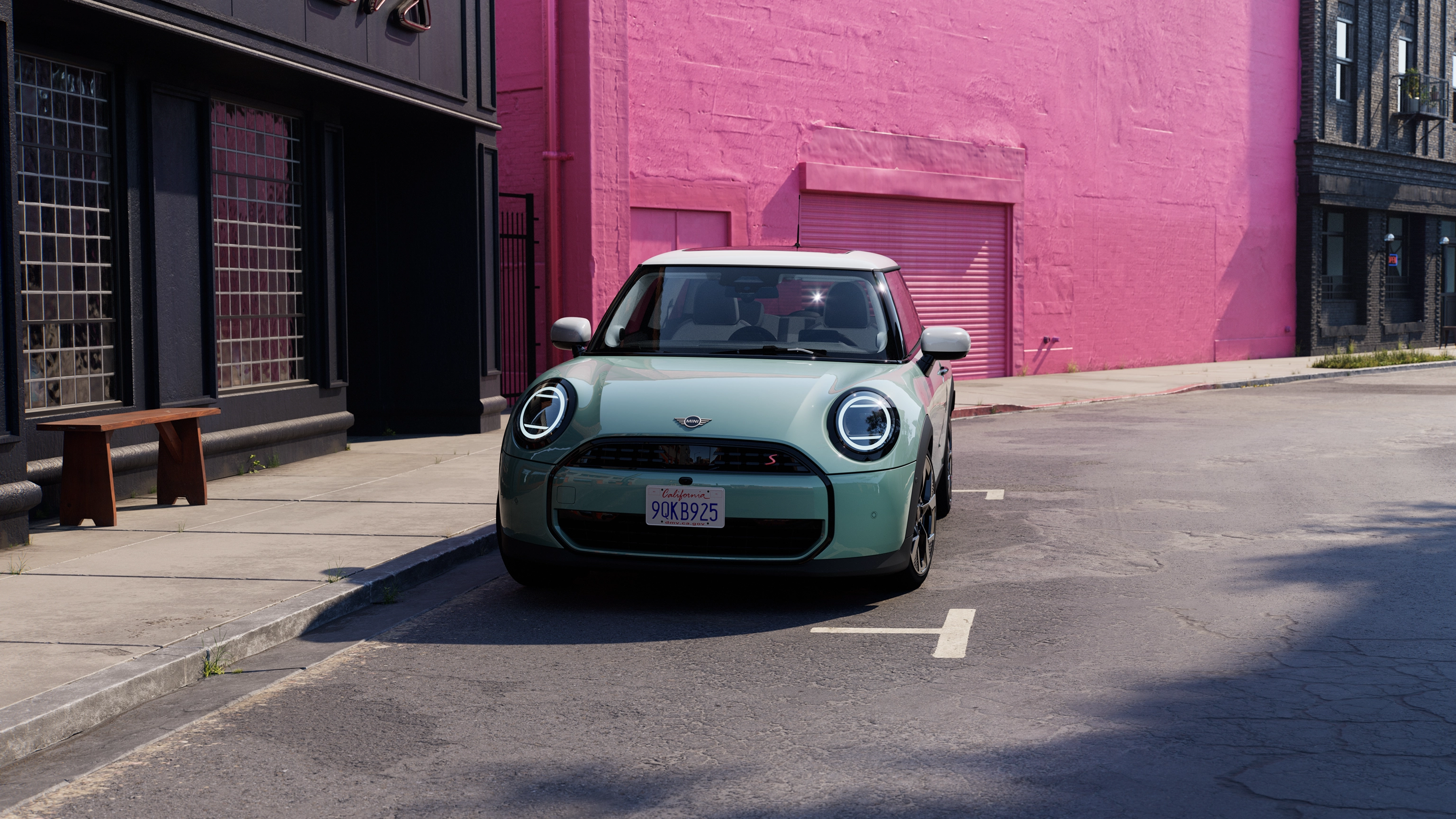 Frontal view of a parking MINI Cooper in Ocean Wave Green and White Roof on street with pink wall in the background