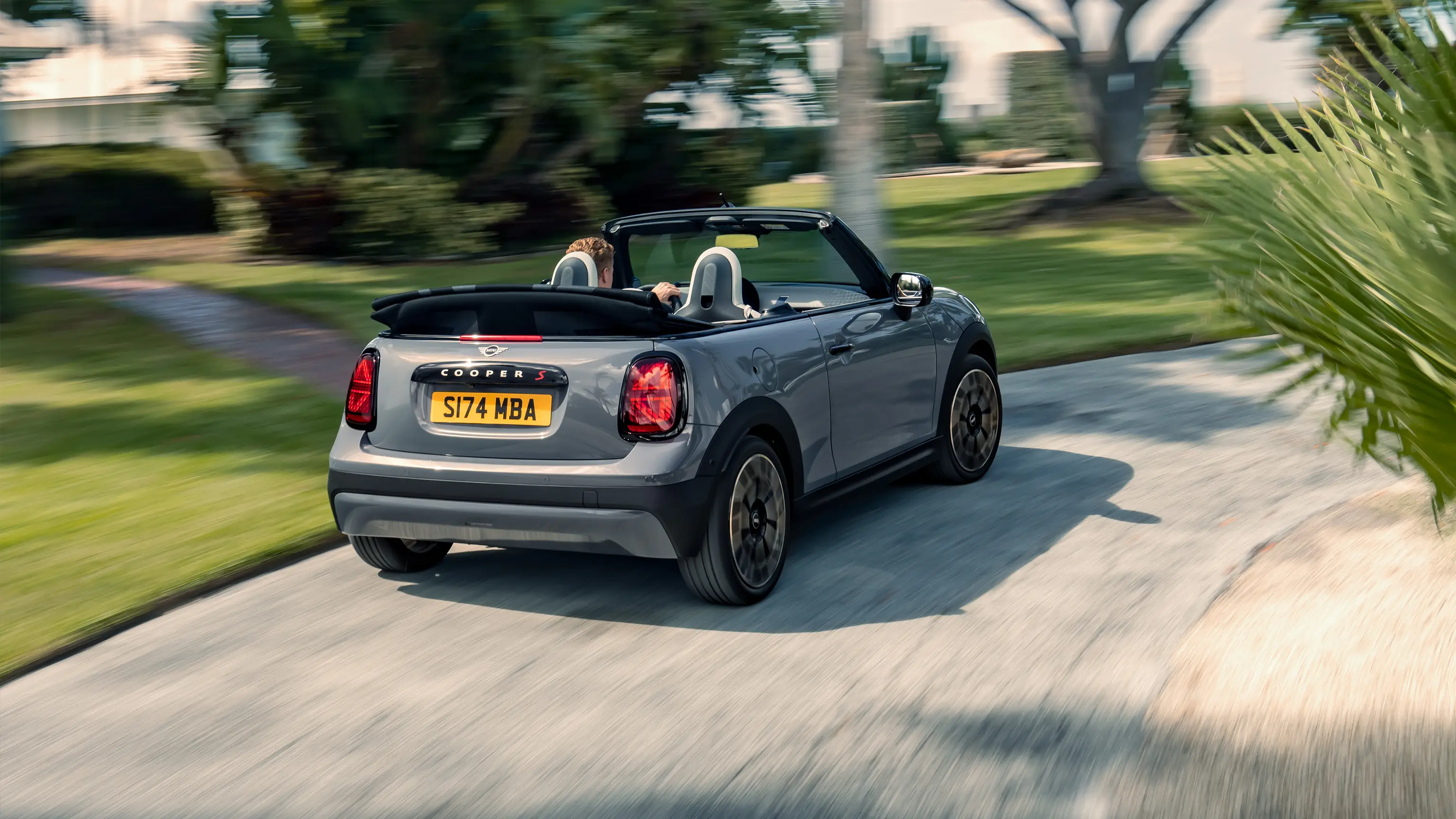 Rear view of a driving MINI Cooper Convertible in Copper Grey