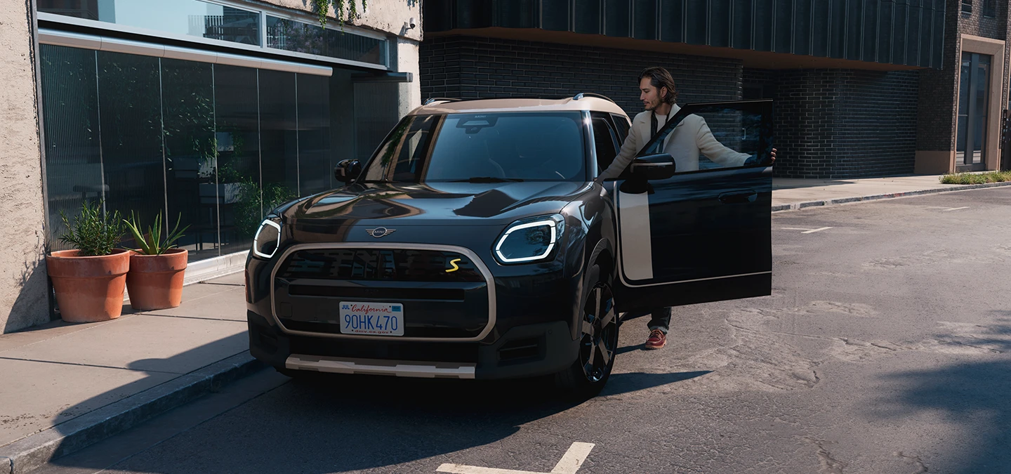 Front view of the all-electric MINI Countryman in Midnight Black and Vibrant Silver Roof on a street.