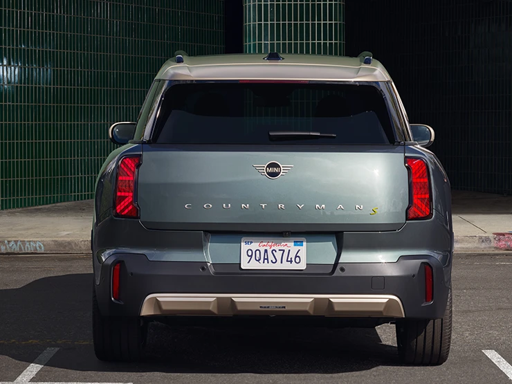 Rear view of the all-electric MINI Countryman in Smokey Green and Vibrant Silver roof parking. 