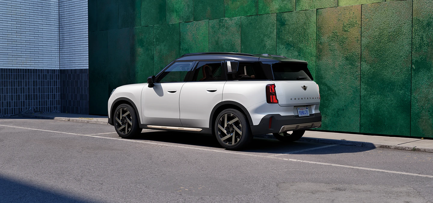 Side rear view of the MINI Countryman in Nanuq White with Black Roof standing on a street.