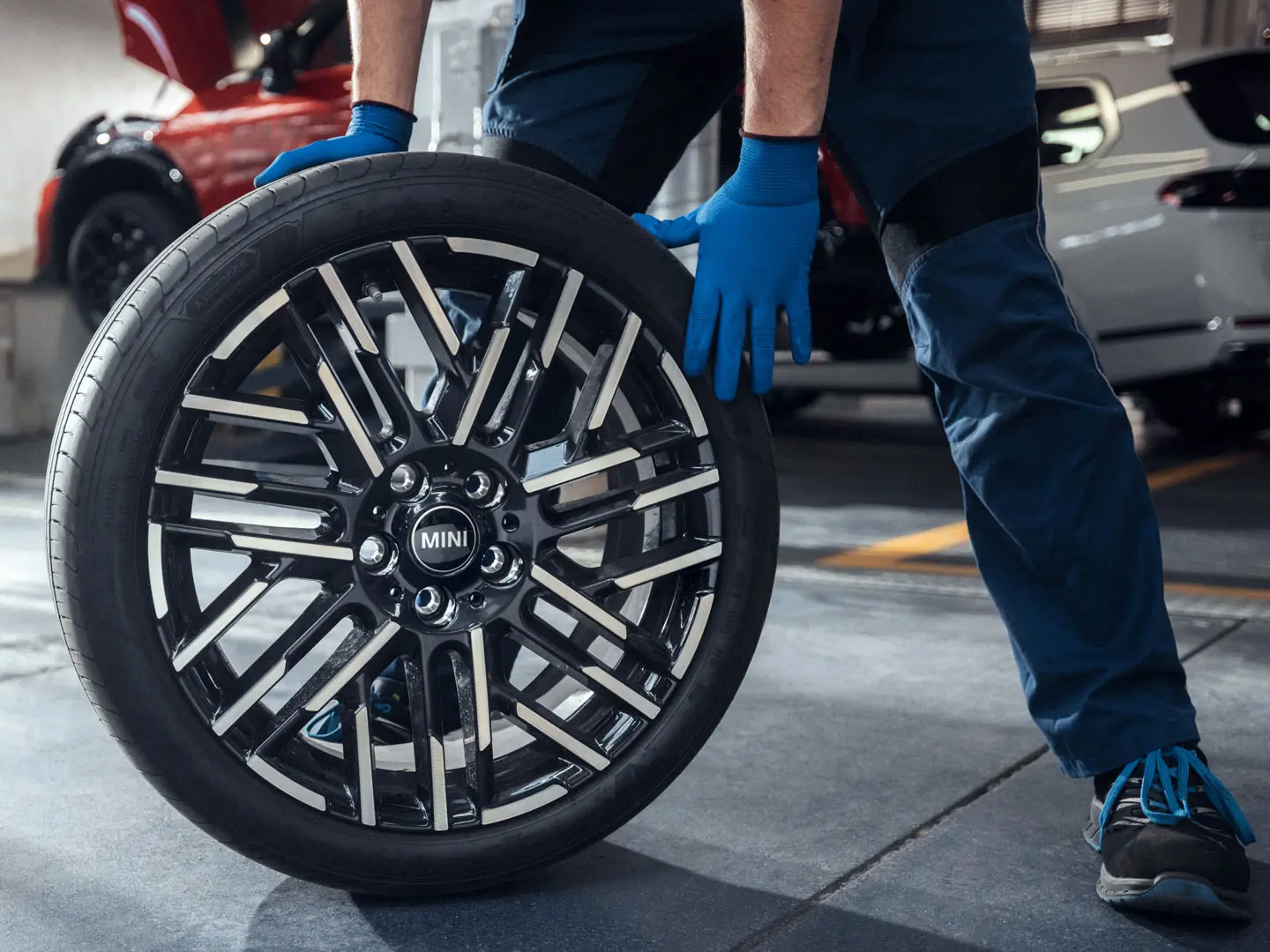 A MINI Partner service technician rolls an 18" Night Flash Spoke Bicolour Light Alloy Wheel into position.