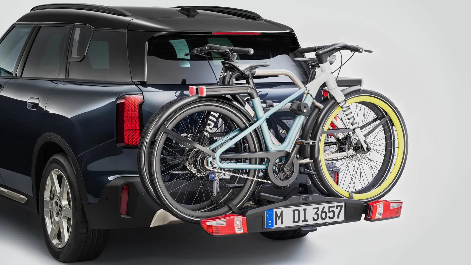 MINI Countryman in black with rear bike carrier and two mountain bikes attached, rear view.