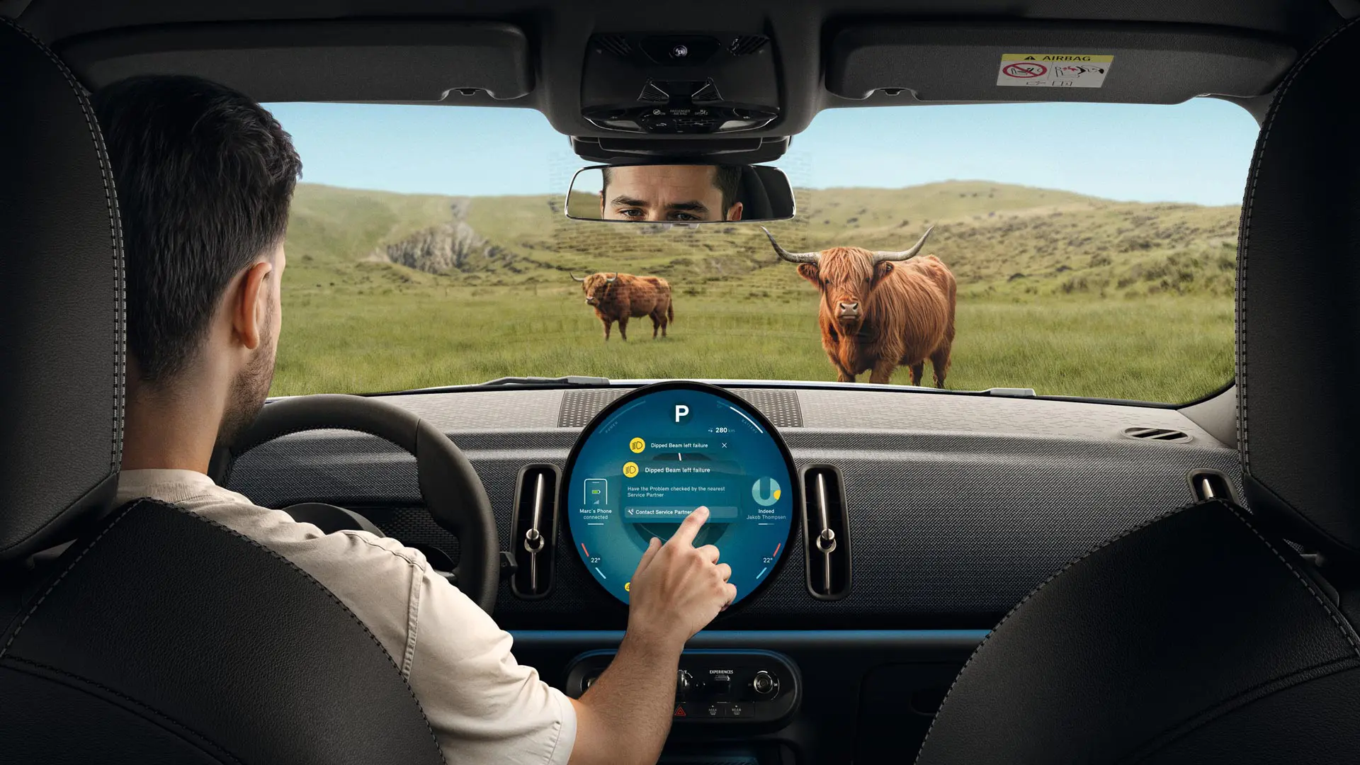 MINI driver on country road blocked by a Highland Bull getting advice from MINI Roadside Assistance via his touchscreen. 