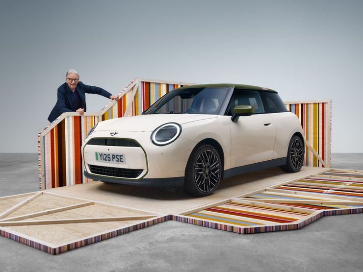 Side view of all-electric MINI Cooper Paul Smith Edition in Inspired White with Paul Smith sitting in the car.