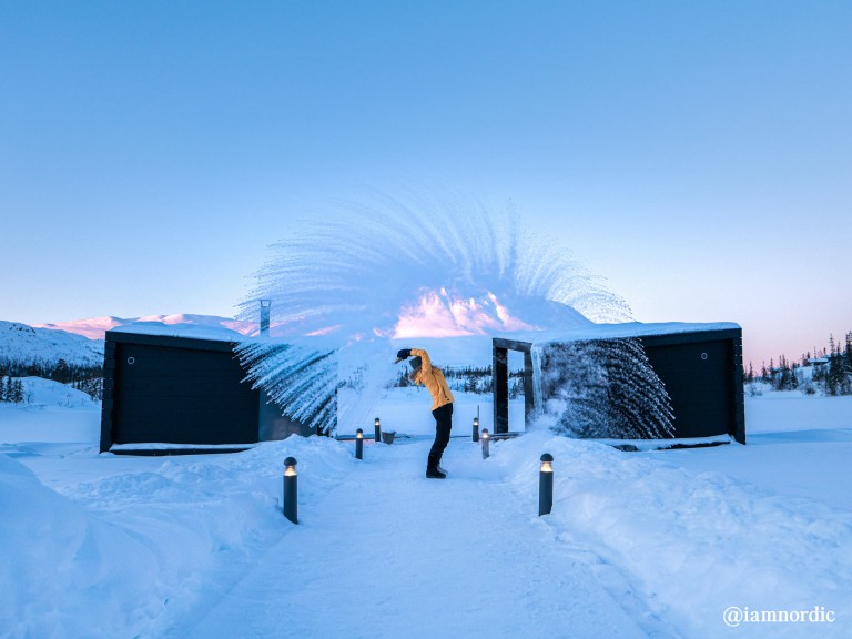 A man in a yellow jacket playing in the snow in the countryside.